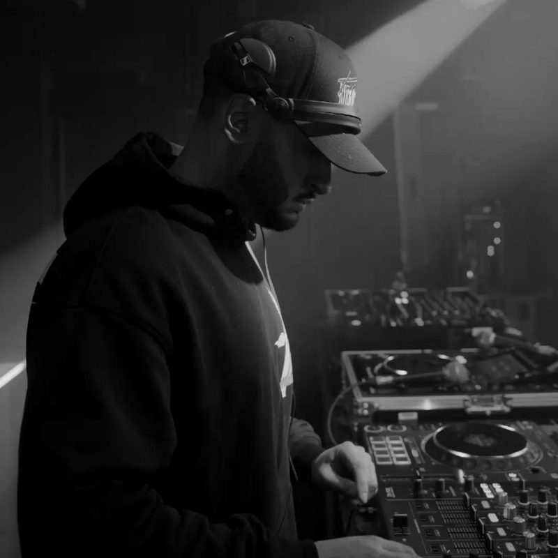 DJ Jeevz mixing in a club under a beam of light